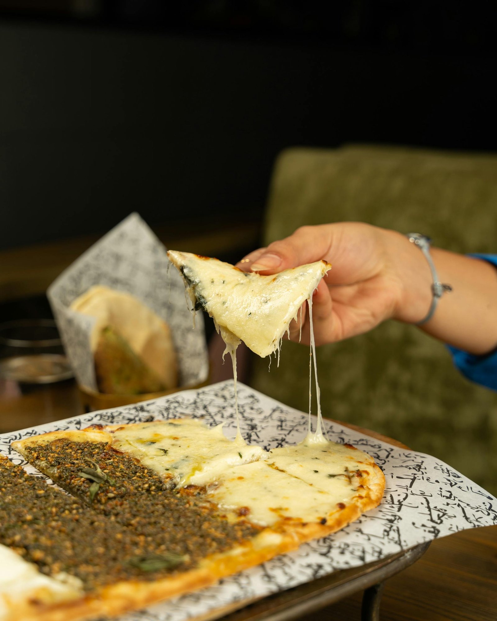 Turkey Travel Guide: Timeless Beauty Across Two Continents 15 A close-up of a hand pulling a cheesy slice from a Turkish pide, showcasing its appetizing texture.