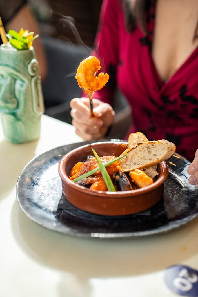 A close-up of a vibrant seafood tapas dish served in a traditional clay pot.
