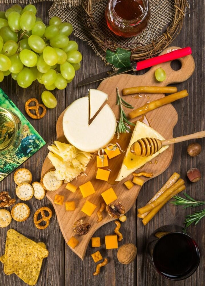 A delicious assortment of cheeses, crackers, and grapes on a wooden board for a gourmet appetizer.