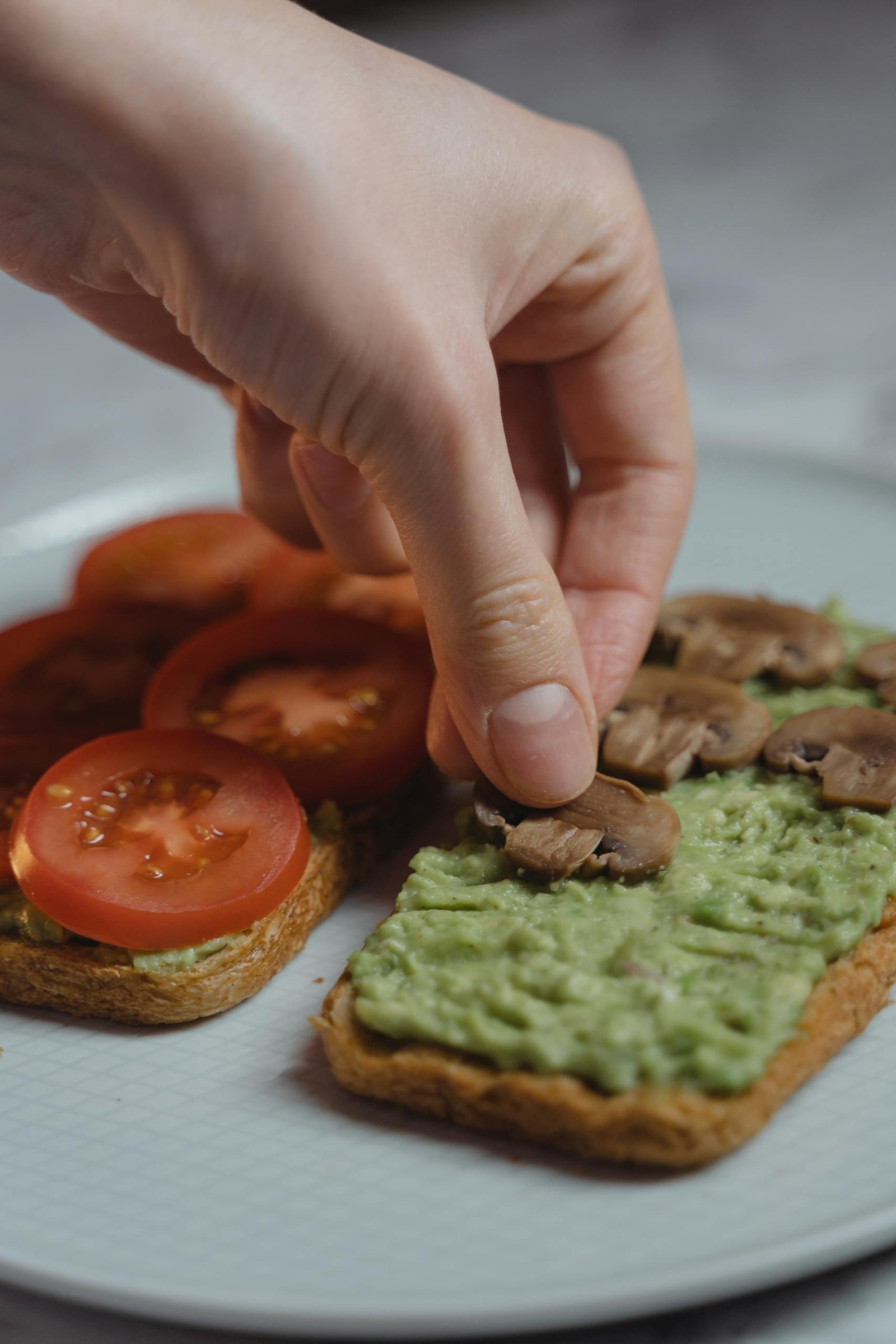 England Travel Guide for first time visitors 14 Close-up of a hand preparing vegan avocado toast with fresh vegetables. Healthy meal option.