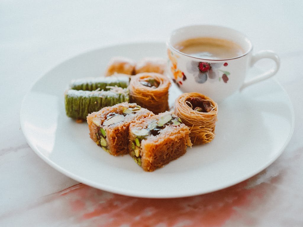 Close-up of assorted baklava and coffee on a decorative plate.