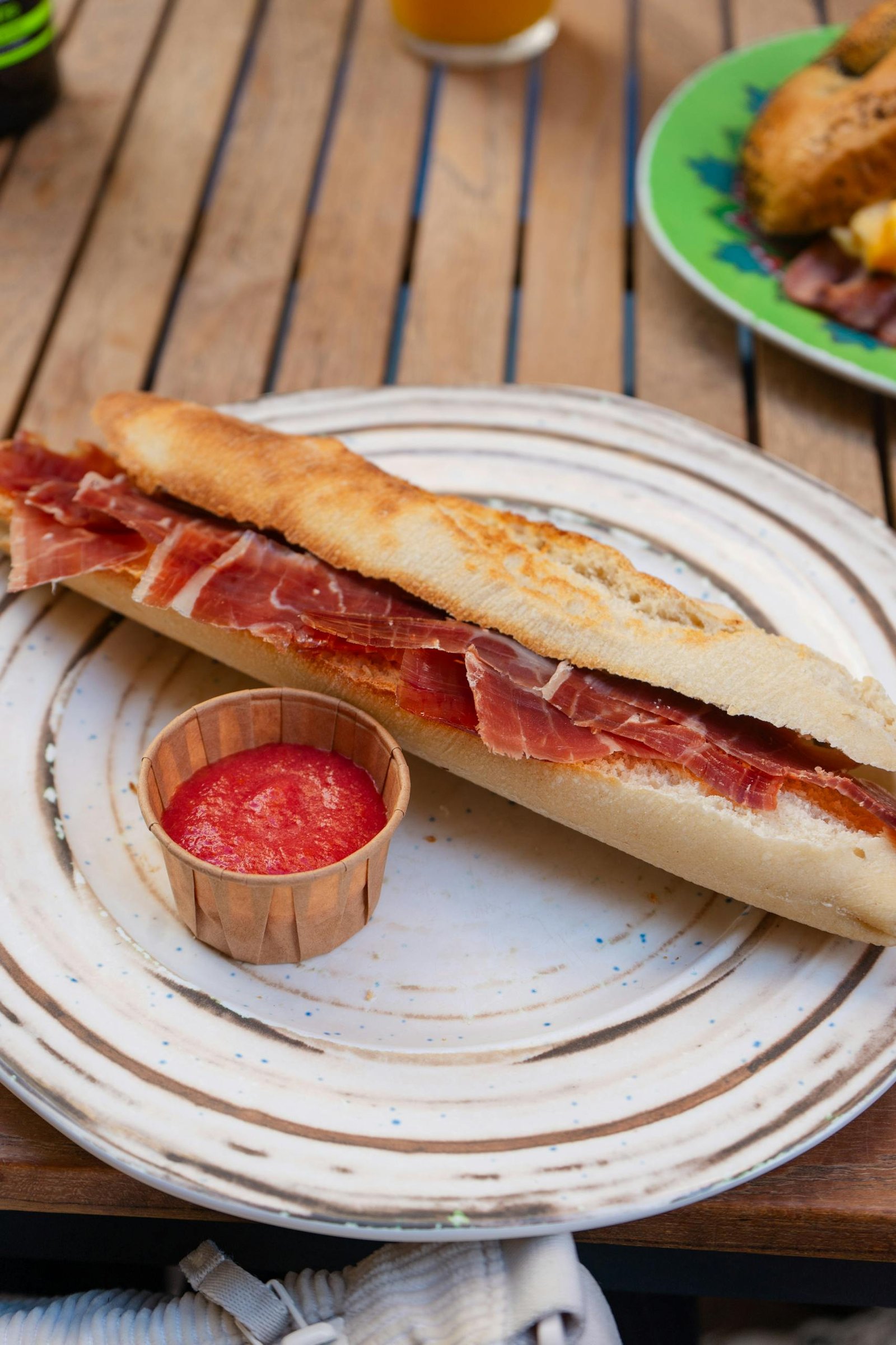Spain Travel Guide: Things to know before travelling to Spain 13 Delicious Spanish bocadillo with jamón and tomato sauce served on a rustic plate outdoors.