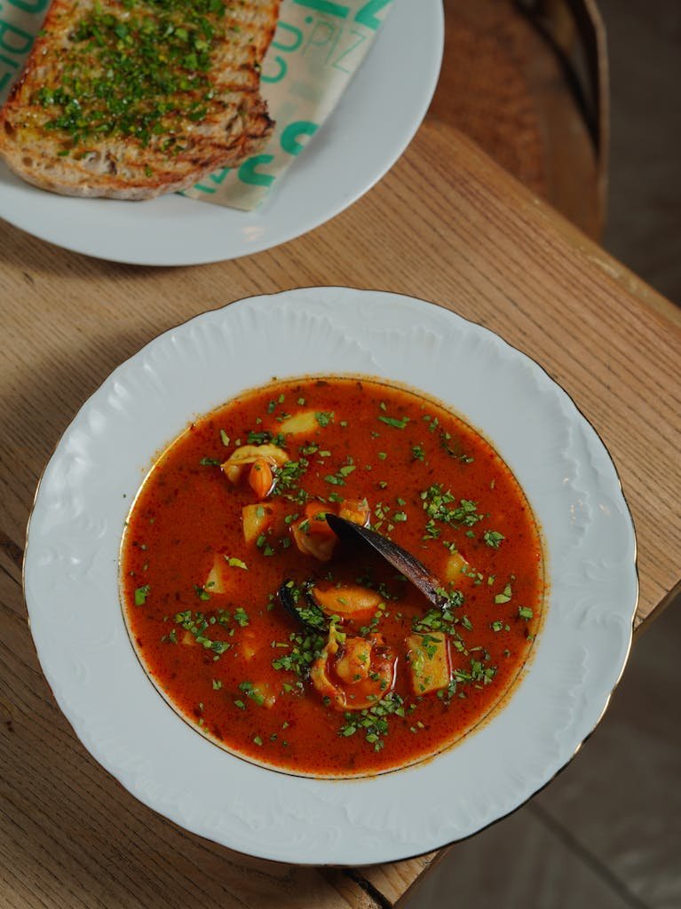 Hearty seafood soup served with herb bread on a rustic table setting.