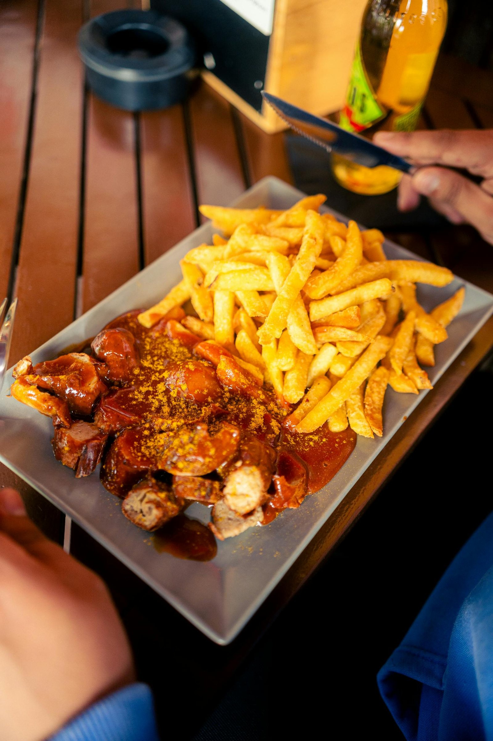 Plate of currywurst with sauce and crispy french fries, a classic fast food meal.