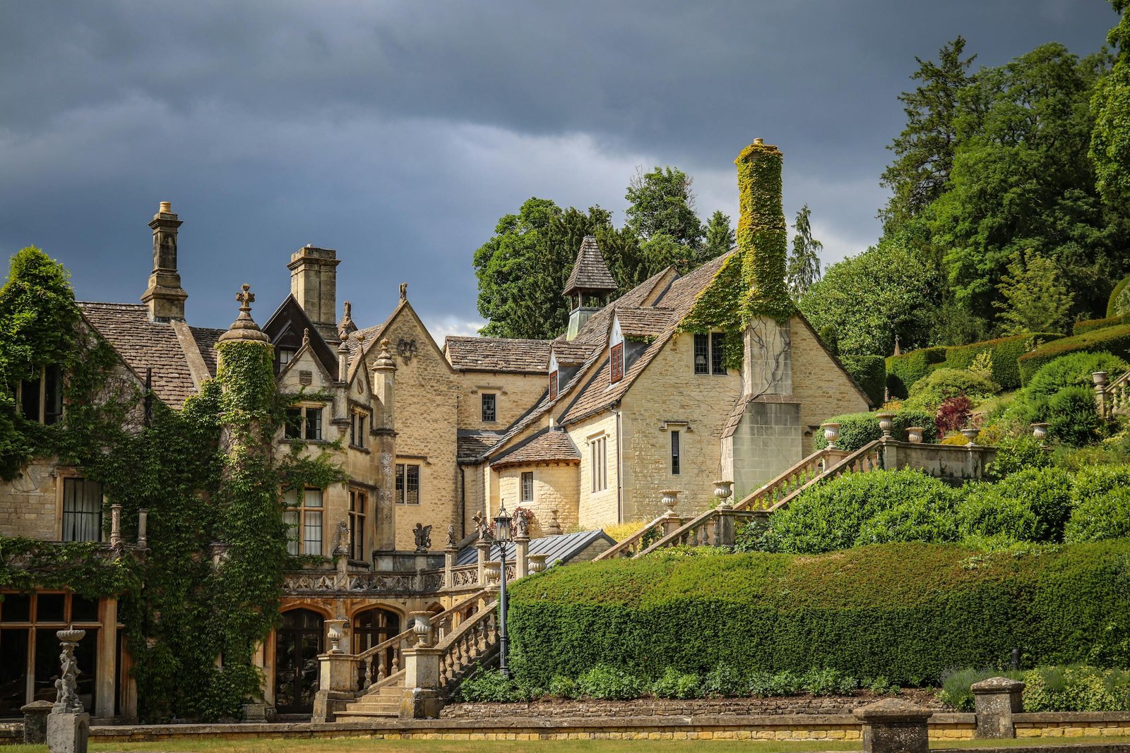 Scenic view of a historic manor house surrounded by lush green gardens in Castle Combe, England.
