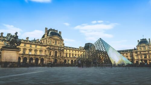 15 Best Chinese Restaurants in Paris (Authentic Flavors You’ll Love) 18 The iconic glass pyramid of the Louvre Museum against a clear blue sky in Paris.