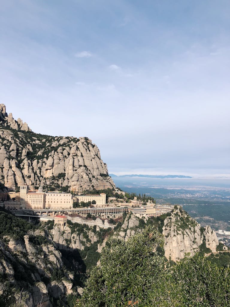 A breathtaking view of Montserrat Monastery set against rugged mountains under a clear blue sky.