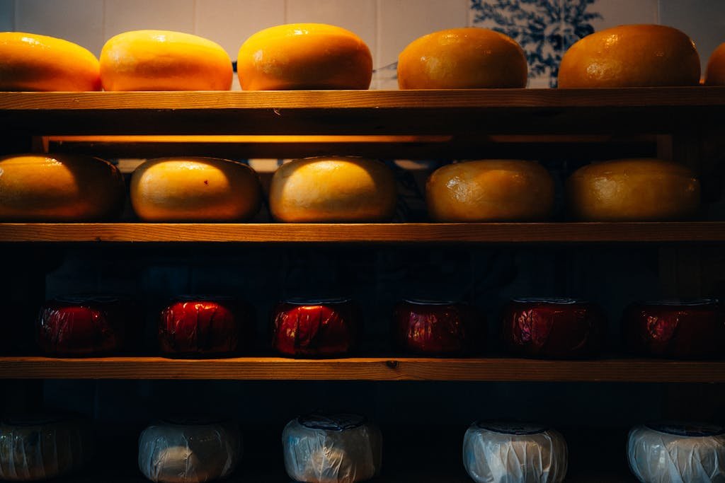 A variety of Gouda and Edam cheese wheels displayed on wooden shelves in Amsterdam.