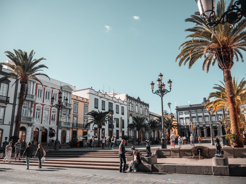 Best Time to Visit Spain: A Complete Guide to Spain's Seasons and Weather 3 A vibrant day in a city square with people and palm trees in Canary Islands, Spain.
