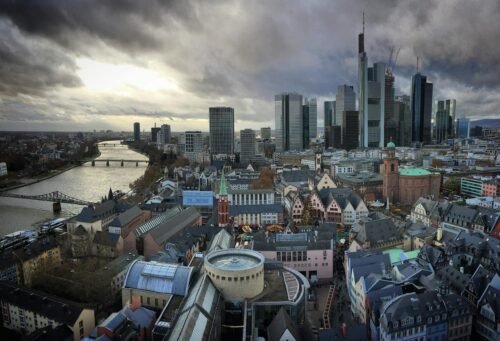 Aerial view of Frankfurt's modern skyline and historic center along the Main river at twilight.