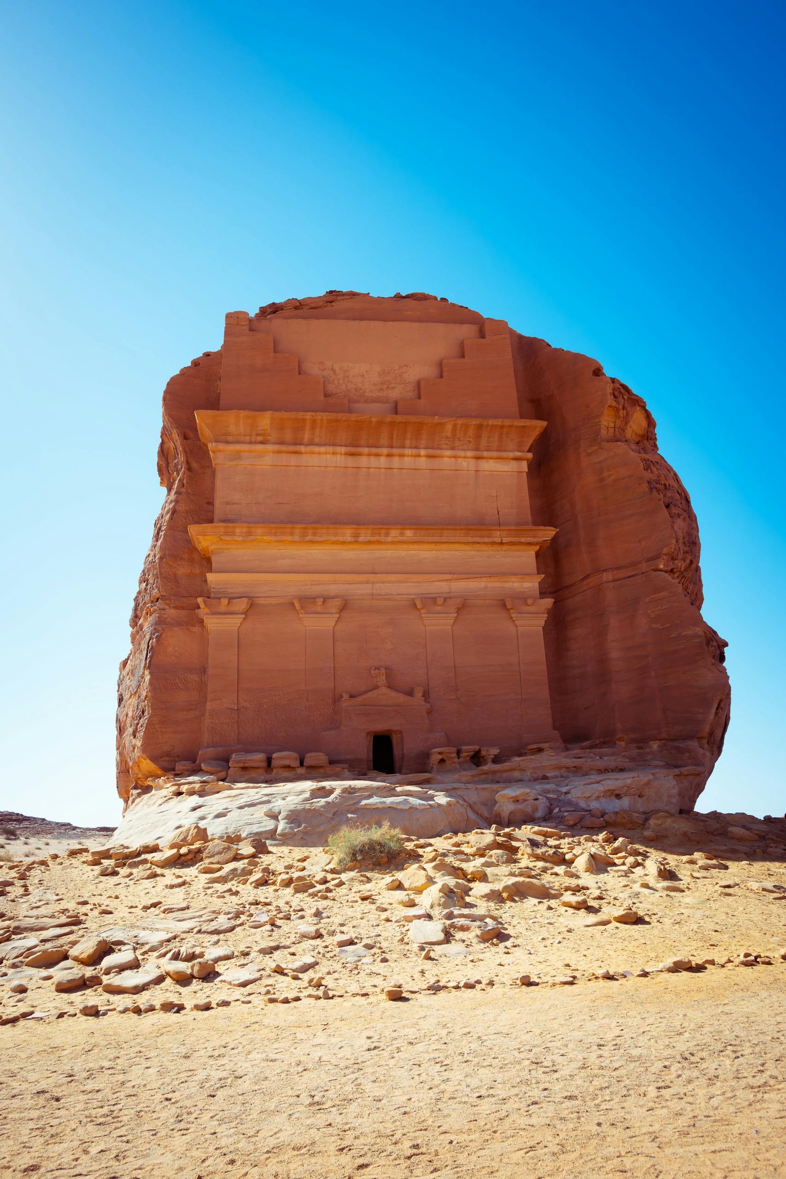 one of the beautiful places in Saudi Arabia Ancient tomb at AlUla, Saudi Arabia, set against a vivid blue sky. A remarkable rock formation.