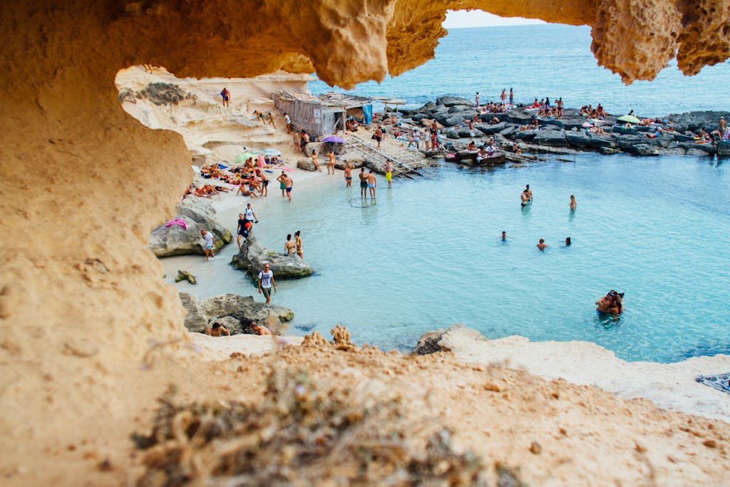 Best Time to Visit Spain: A Complete Guide to Spain's Seasons and Weather 2 Best time to visit Spain A picturesque beach scene in Spain with people enjoying swimming and sunbathing by rock formations.