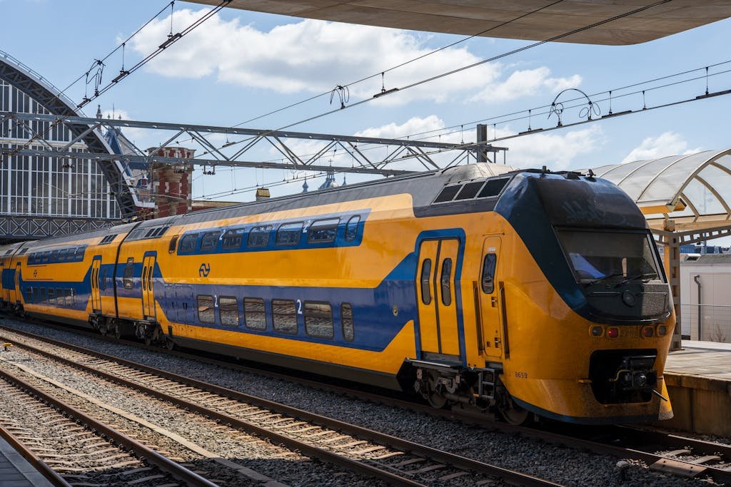 Bright yellow double-decker train at Amsterdam railway station under a clear sky easiest way to getting around Amsterdam