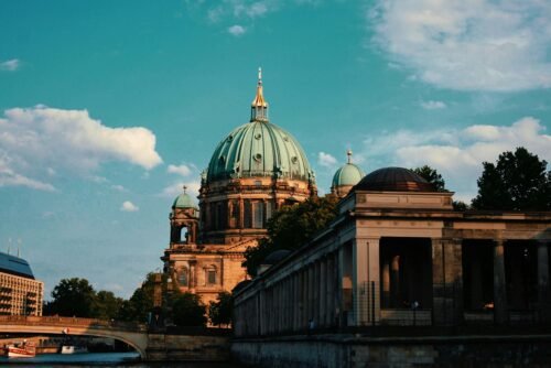 Capture the elegance of Berlin Cathedral with a serene river view during sunset.