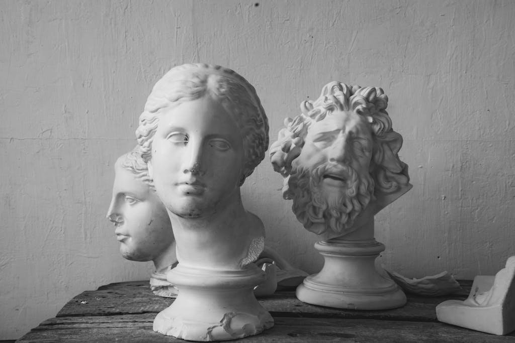 Collection of monochrome classical sculpture busts on a wooden surface, ideal for art themed projects.
