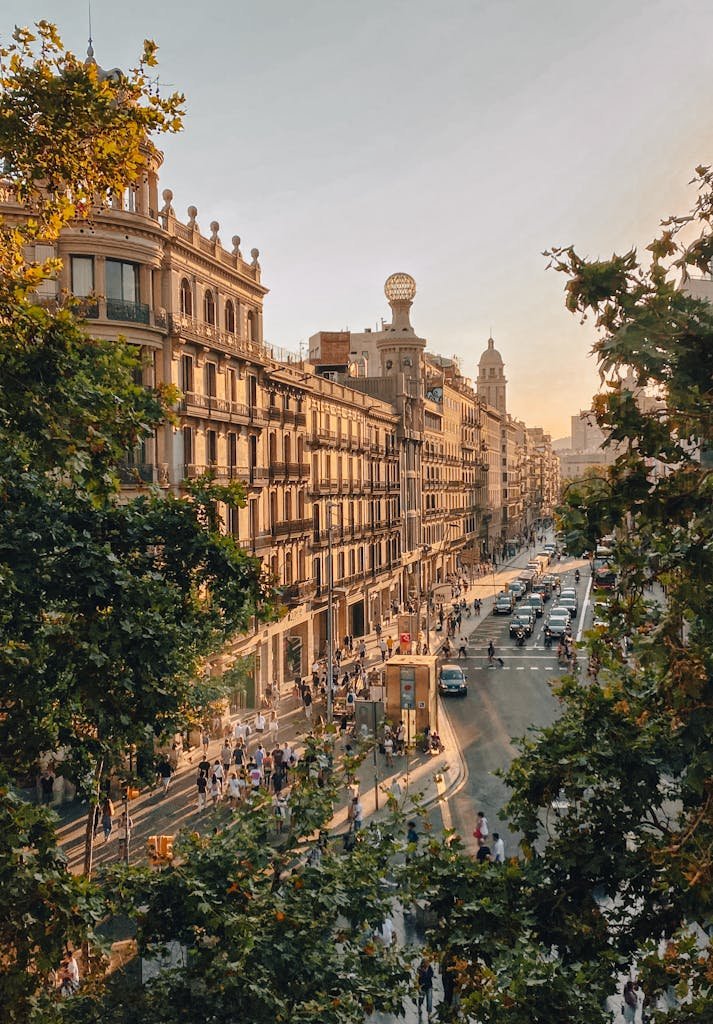 Golden hour view of a bustling street in Barcelona, showcasing classic architecture amidst urban vibrancy.