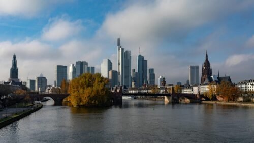 Scenic view of Frankfurt am Main's skyline with skyscrapers and river under clear blue sky.