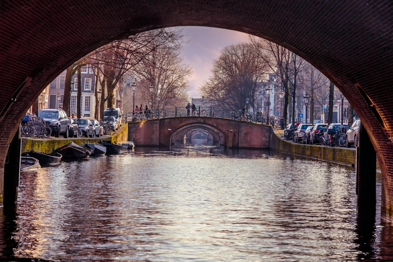 Stunning view of Amsterdam canal framed by a bridge arch capturing the city’s iconic architecture and tranquil waters.