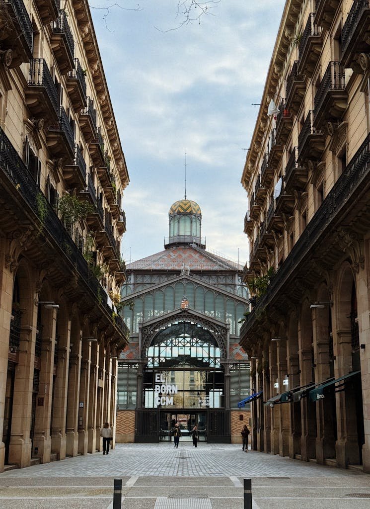 View of El Born Market entrance nestled between historic buildings.