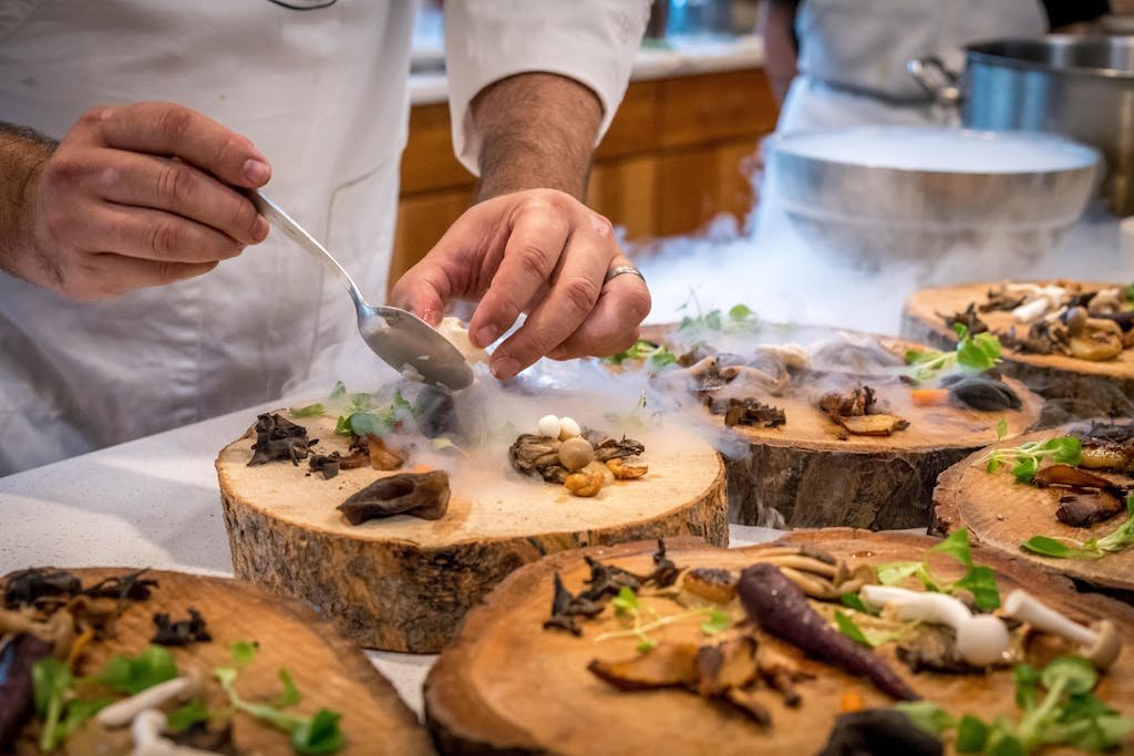 15 Best Chinese Restaurants in Paris (Authentic Flavors You’ll Love) 8 A chef artfully plating a gourmet dish with mushrooms and greens on wood slices.