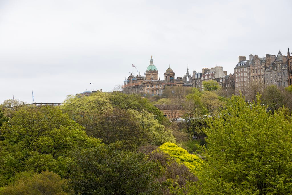 45 Unique Things to Do in Edinburgh: Hidden Spots & Must-See Attractions 22 Beautiful view of Edinburgh's architecture surrounded by lush greenery on a cloudy day.