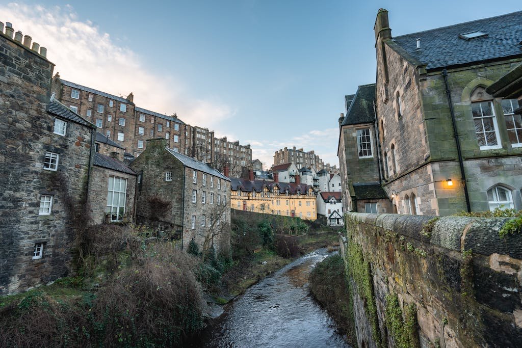 45 Unique Things to Do in Edinburgh: Hidden Spots & Must-See Attractions 25 Charming view of Edinburgh's classic stone architecture by a peaceful river in Scotland.