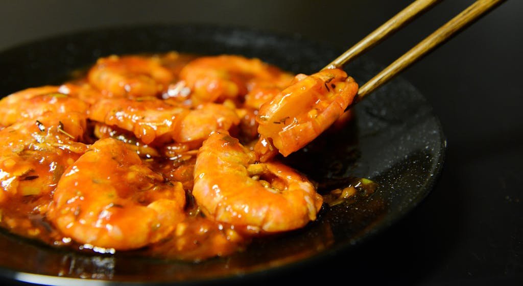 15 Best Chinese Restaurants in Paris (Authentic Flavors You’ll Love) 16 Close-up of spicy prawns in sauce with chopsticks on a dark plate