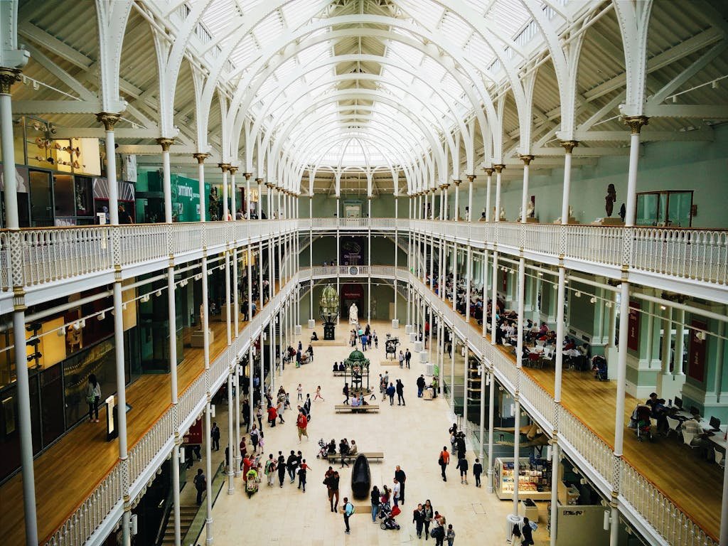 45 Unique Things to Do in Edinburgh: Hidden Spots & Must-See Attractions 7 Interior view of the National Museum of Scotland's grand hall with visitors exploring exhibits.