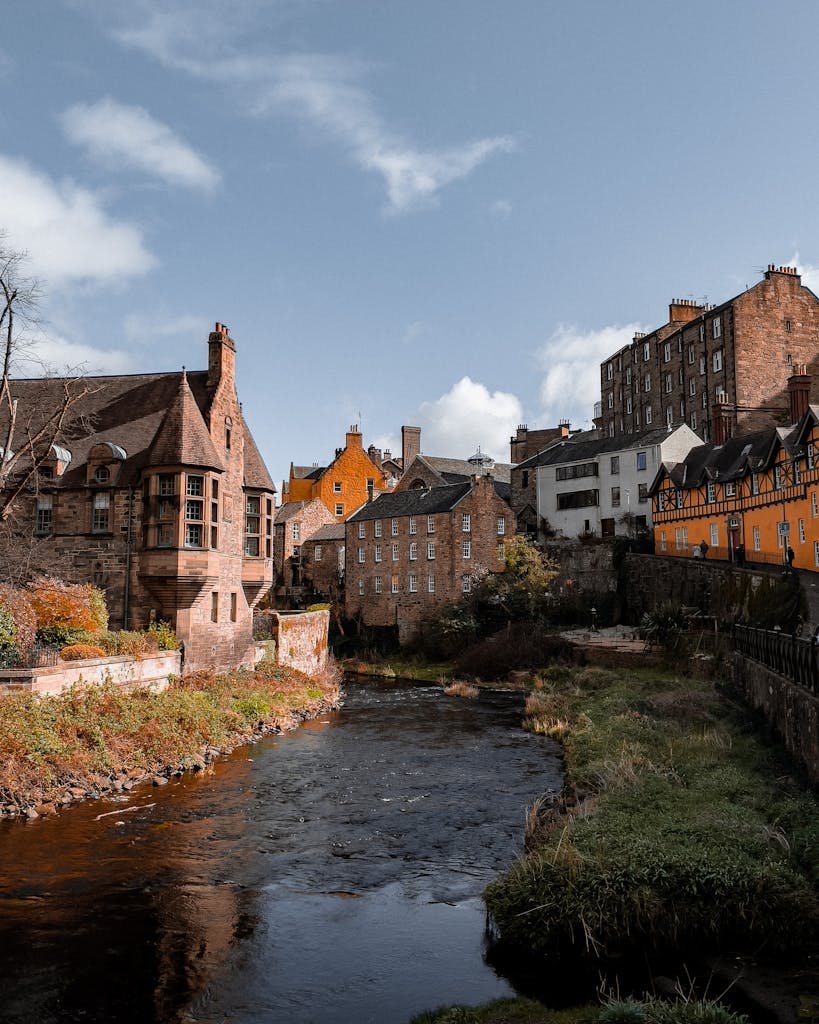 45 Unique Things to Do in Edinburgh: Hidden Spots & Must-See Attractions 24 Scenic view of historic Dean Village architecture by a flowing stream in Edinburgh.