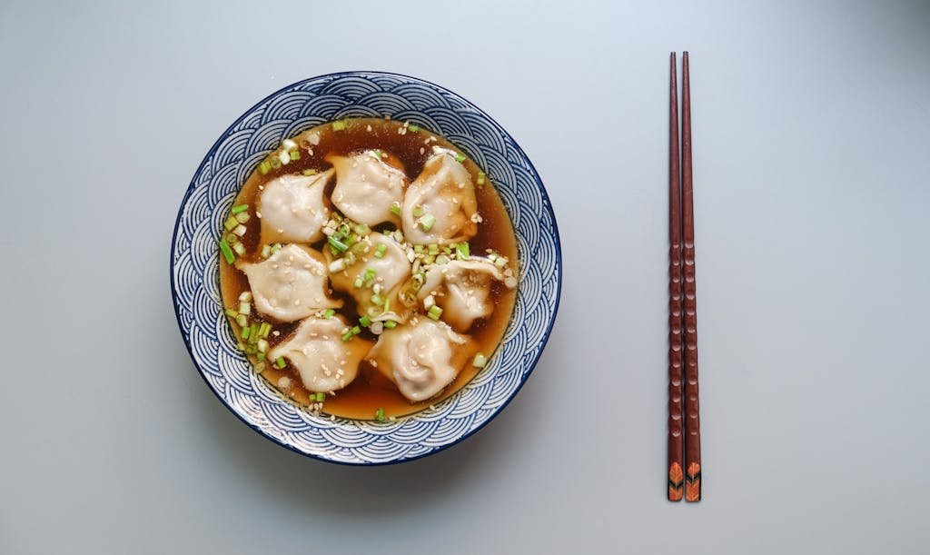 15 Best Chinese Restaurants in Paris (Authentic Flavors You’ll Love) 4 Top view of a bowl of dumplings in soup garnished with scallions.