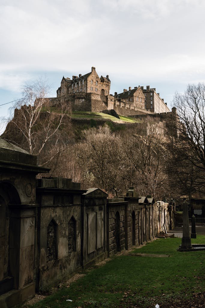 45 Unique Things to Do in Edinburgh: Hidden Spots & Must-See Attractions 4 View of Edinburgh Castle and stone walls framed by bare trees in winter's cool daylight.