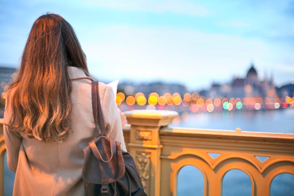 A woman enjoys a scenic view of Budapest's Danube River with bokeh lights in the background.
