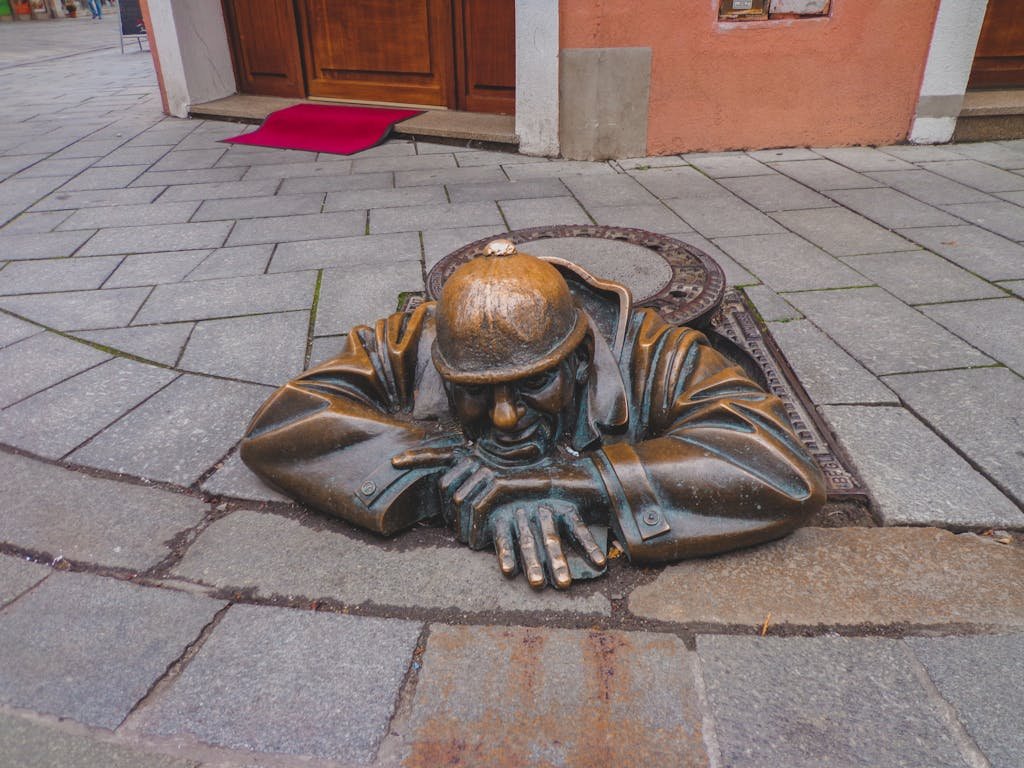 3 Magical Days in Prague (My Prague travel Itinerary) 12 Bronze statue of a man emerging from a manhole on a Prague sidewalk, a unique urban sculpture.