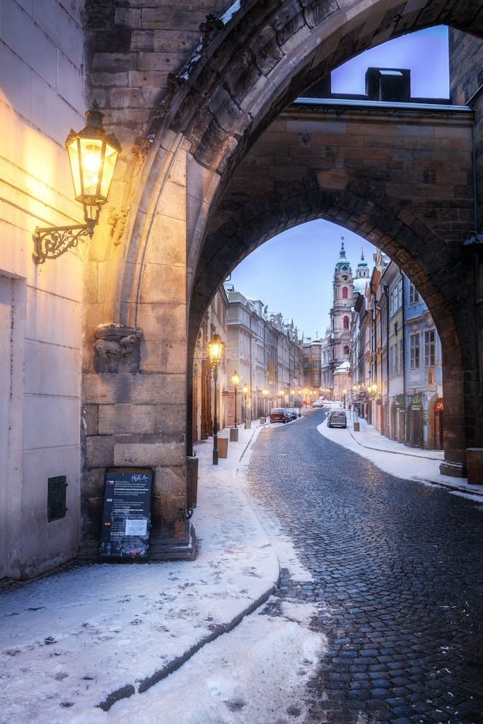 3 Magical Days in Prague (My Prague travel Itinerary) 9 Enchanting winter scene under an arched entrance in historic Prague's cobblestone street.