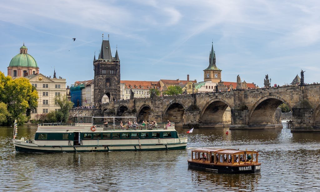 Explore a vibrant cruise along Prague's Vltava River with the iconic Charles Bridge in view.