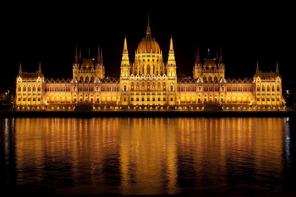 Illuminated view of the Hungarian Parliament Building reflecting in the Danube at night.