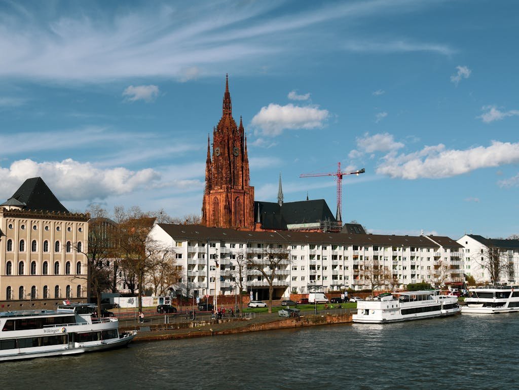Magnificent view of Frankfurt Cathedral and waterfront with tour boats on a sunny day.