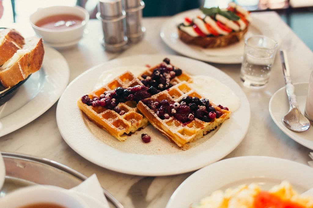 3 Magical Days in Prague (My Prague travel Itinerary) 6 Plate of waffles with berries and cream at a cozy breakfast setup.