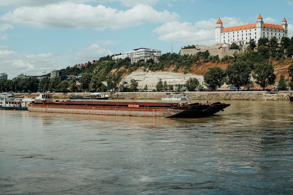 15 Best Things To Do In Bratislava, Slovakia: Day Trip Itinerary 1 A picturesque barge cruising the Danube river with Bratislava Castle in the background.