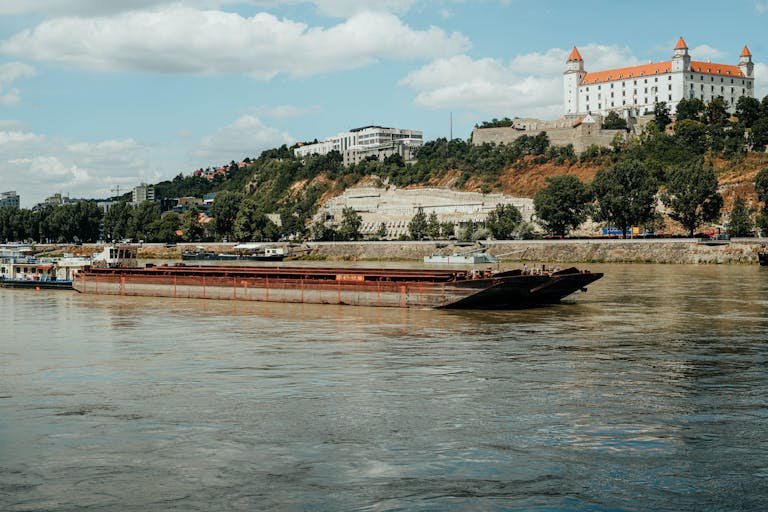 A picturesque barge cruising the Danube river with Bratislava Castle in the background.