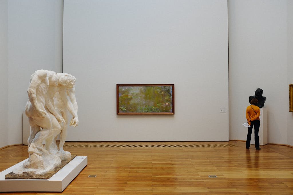 A visitor examines sculptures and paintings at an art museum.