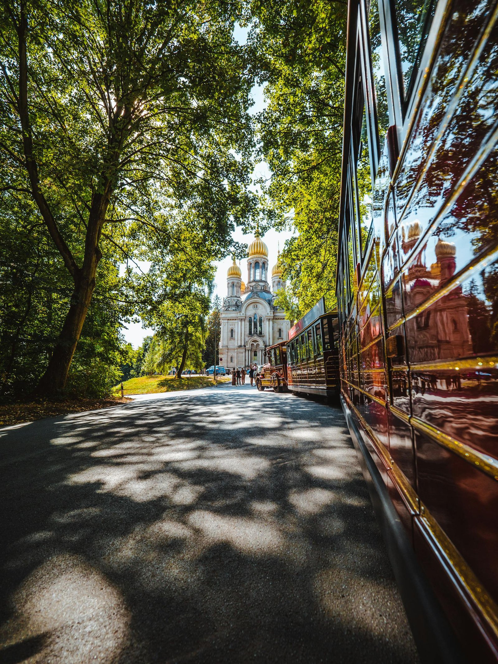 Beautiful view of St. Elizabeth's Church in Wiesbaden with a tourist train under lush green trees.