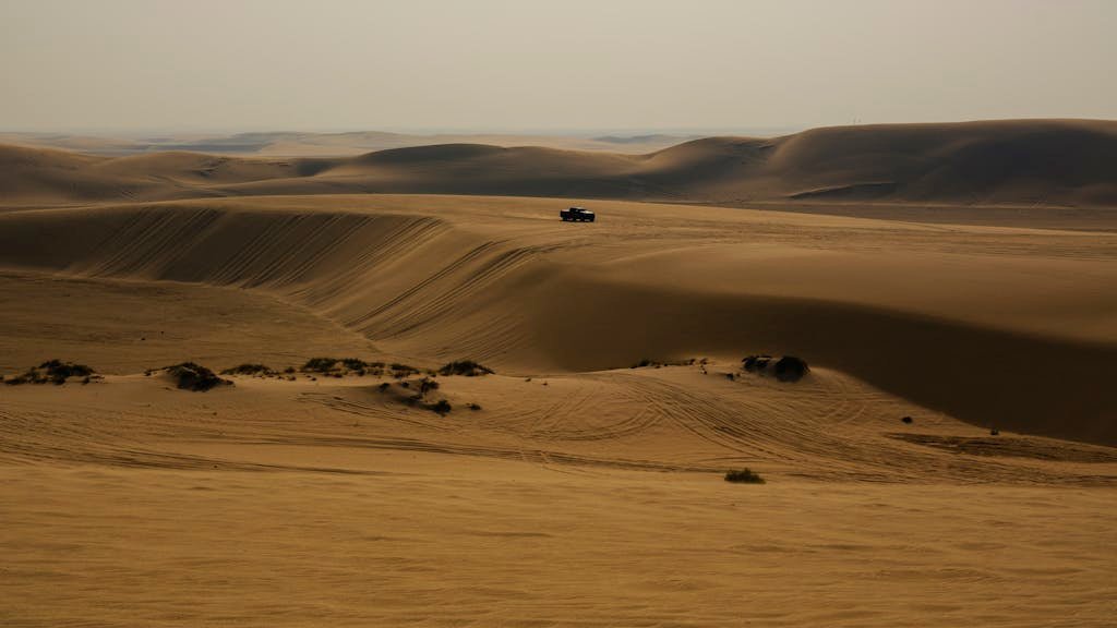 Expansive aerial view of arid desert sands near Doha, capturing the beauty of the dunes.