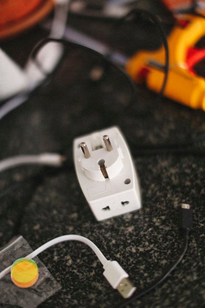 Universal plug adapter and charging cables on a cluttered desk.