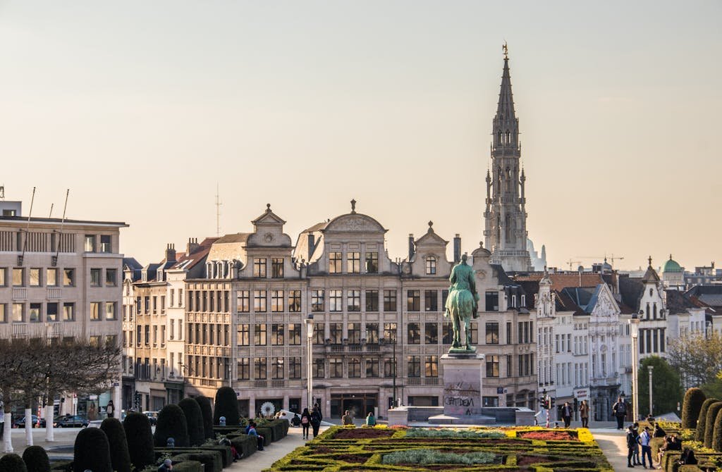 A beautiful cityscape of Brussels with the iconic Town Hall tower and vibrant gardens.