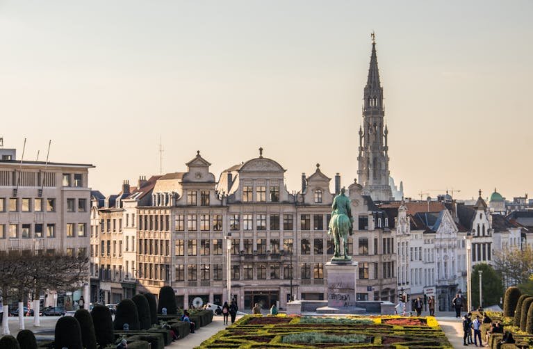 A beautiful cityscape of Brussels with the iconic Town Hall tower and vibrant gardens.