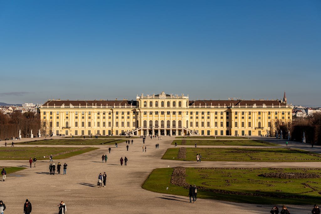 5 Days in Austria: The Perfect Austria Road Trip Itinerary 11 A frontal view of Schönbrunn Palace in Vienna, Austria, with people strolling the gardens.