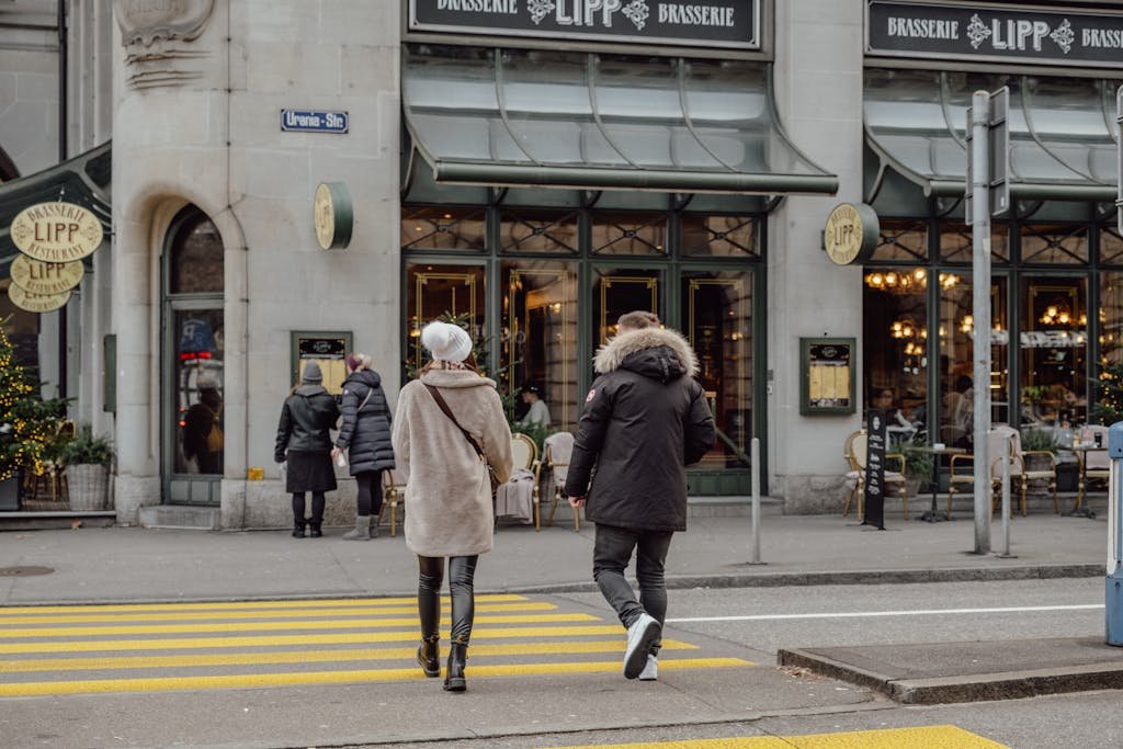 How to Spend the Perfect 5 Days in Switzerland Itinerary? 5 Adults crossing the street in front of Brasserie Lipp in Zurich, Switzerland.