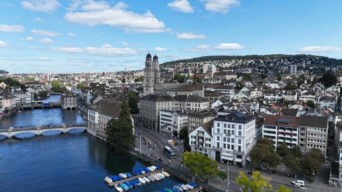 16 Amazing Things to Do in Zurich for First-Time Visitors 1 Aerial cityscape of Zurich, showcasing historic architecture, river, and Limmatquai under a vibrant blue sky.