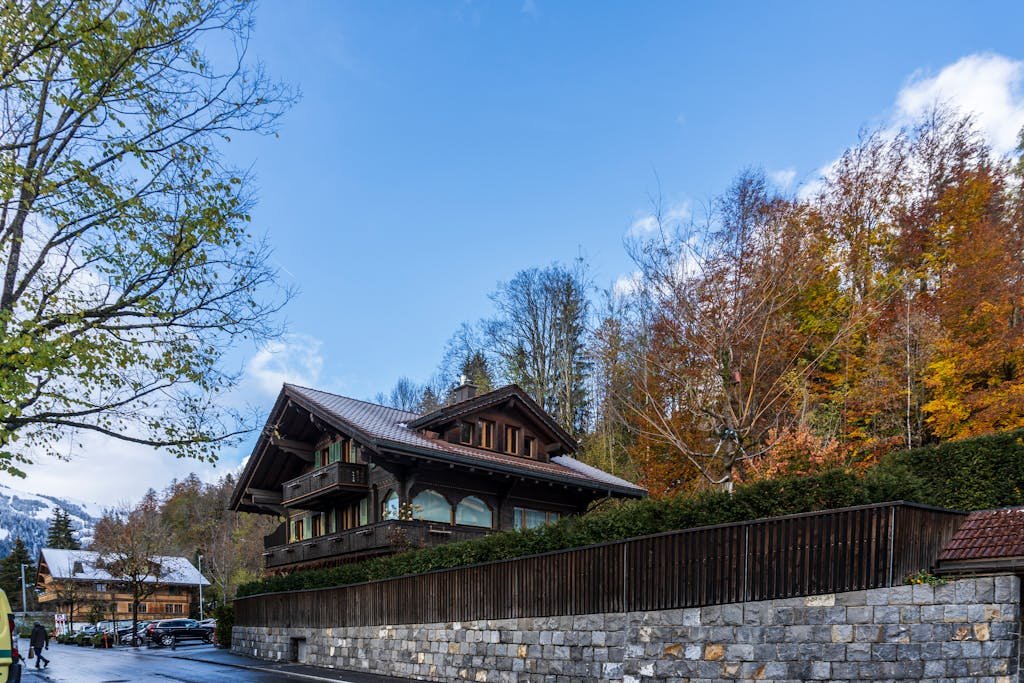 How to Spend the Perfect 5 Days in Switzerland Itinerary? 16 Beautiful Swiss chalet surrounded by vibrant autumn foliage in Saanen, Bern, Switzerland.